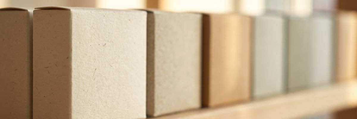 A tight row of small plain boxes standing on a shelf, receding into soft focus.