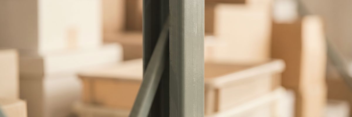 A steel shelving upright close to the lens and out of focus, boxes blurred behind it.
