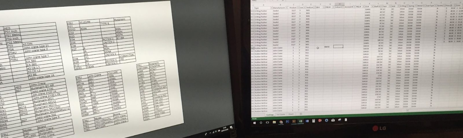 Two monitors side by side, both filled with spreadsheets — a parts cross-reference chart on the left, a costings sheet on the right.